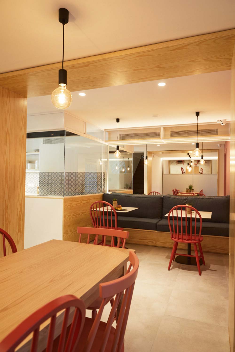 Brunch shop interior, view of table arrangement with build in sofa, red chairs and a big mirror.