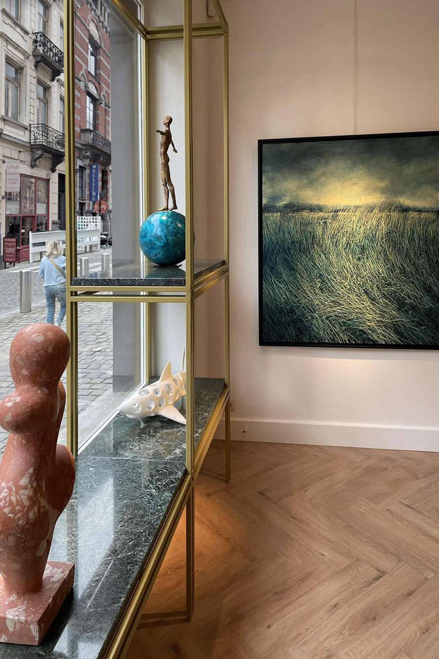 The golden metal structure with the stunning green marble shelves is the unique element in the shop window. 