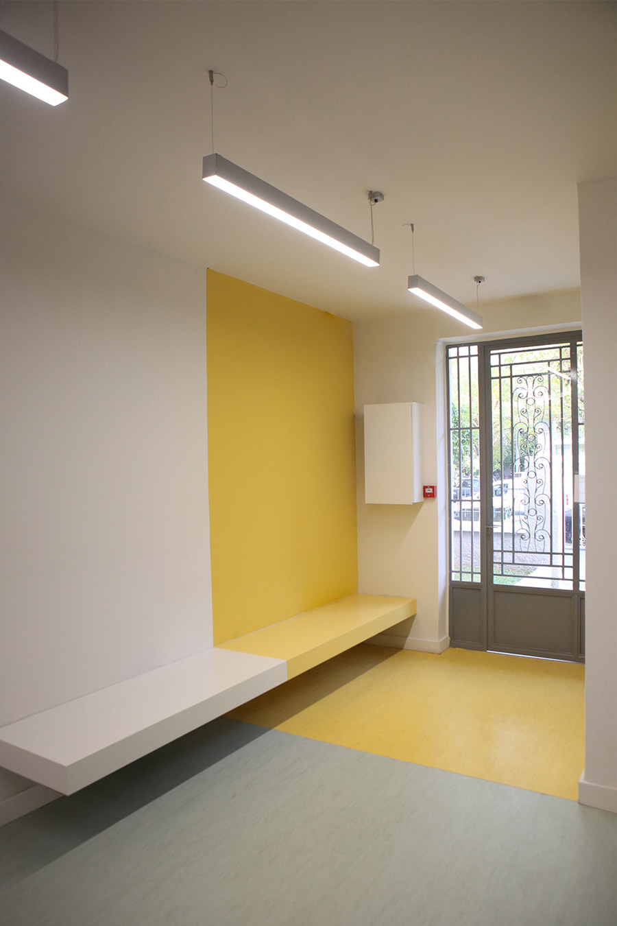 The waiting area is a minimal bench in beige and white colours