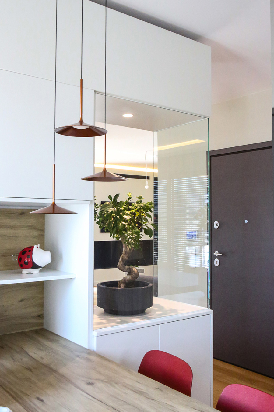 Kitchen view with white lacquered finish and red chairs.